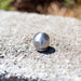 Stainless steel ball jet sewer jetter nozzle on asphalt surface, high-pressure drain cleaning nozzle for hydro jetting, durable multi-port jet nozzle for clearing pipes, grease, and debris in plumbing and sewer lines