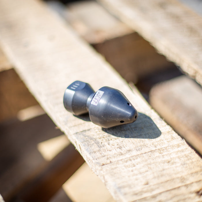 US Jetting RPD Egghead Penetrator nozzle made of case‑hardened steel, shown outdoors on a wooden pallet with visible 407 marking, featuring a rounded nose and two‑piece removable cap for easy cleaning; high‑pressure sewer jetting nozzle engineered with forward and rear jets for cutting through blockages, heavy grease, and root masses, compatible with 1/2", 3/4", and 1" hoses and rated for 14–65 GPM at 2,000–10,000 PSI.