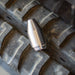 Stainless steel high‑pressure jetting nozzle on rugged tire tread, precision‑machined conical cleaning and cutting tool engineered for hydro‑excavation and industrial surface preparation using a rotating zero‑degree water stream.