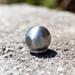 Stainless steel ball jet nozzle on a asphalt surface, high-pressure sewer jetting nozzle for drain and pipe cleaning, durable hydro jetting ball nozzle for removing grease, debris, and blockages in plumbing systems.