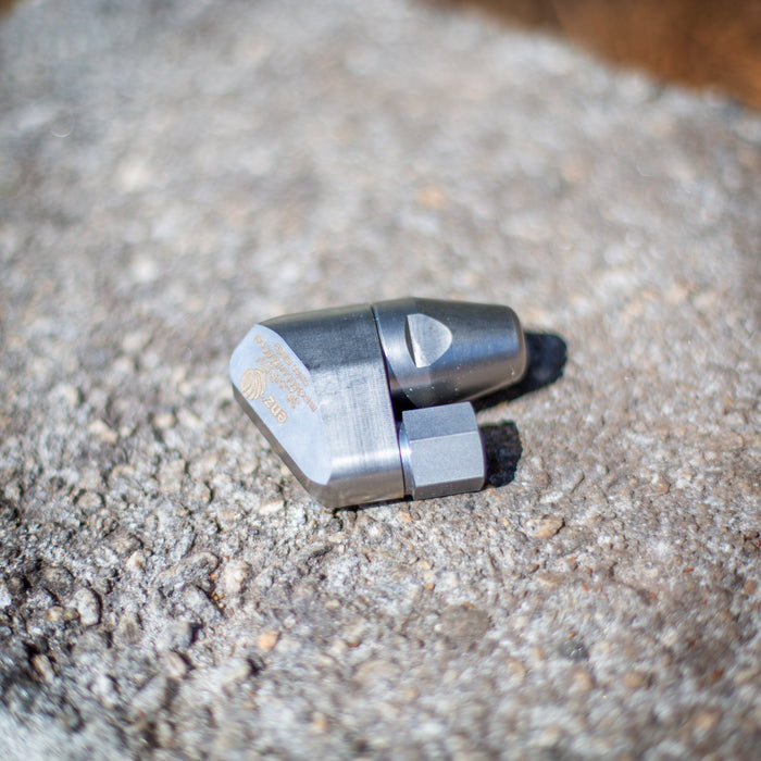 ENZ Bend Rotodrill sewer jetting nozzle with stainless‑steel tapered front, hex‑base connection, and engraved markings, shown on a rough concrete surface; 2¾‑inch rotating jet nozzle designed to negotiate bends and traps while clearing roots, debris, and blockages in 3–6 inch pipes at flows as low as 4 GPM, available in 1/4‑inch and 3/8‑inch connections.