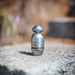 Stainless steel ENZ‑style high‑pressure sewer jetting nozzle marked “D.R.I.L.L.C.37” on a concrete surface, featuring a precision‑machined conical tip and durable body engineered for controlled rotation with an oil‑free braking system; compatible with fresh or recycled water and designed for cutting grease, roots, and heavy pipeline deposits using powerful rear and forward jet patterns, with optional 90‑degree descaling jets available for removing tough scale from pipe walls.