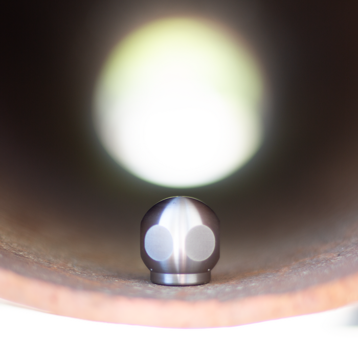 Stainless steel ball jet nozzle centered inside a metal pipe, high-pressure sewer jetting nozzle for drain and pipe cleaning, durable hydro jetting ball nozzle for removing grease, debris, and blockages in plumbing systems