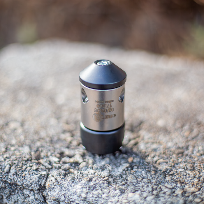 HRV Nozzle Precision metal sewer‑jetting nozzle with engraved specifications, conical jet head and cylindrical body, resting on a textured stone surface; high‑quality industrial nozzle used in professional drain, pipe, and sewer cleaning applications.