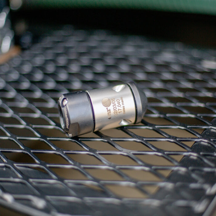 HRV Nozzle - Precision‑machined Swiss‑made metal tool component with engraved markings, shown on a black industrial grid surface; high‑quality cylindrical fitting used in professional mechanical and manufacturing applications.”