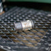 HRV Nozzle - Precision‑machined Swiss‑made metal tool component with engraved markings, shown on a black industrial grid surface; high‑quality cylindrical fitting used in professional mechanical and manufacturing applications.”