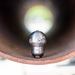 3/8-inch Warthog Mini SuperSpin WT sewer jetting nozzle inside pipe, stainless steel 4000 PSI 12 GPM rotating drain cleaning nozzle with 2 rear jets and 1 forward jet for grease, hair roots, and 3–6 inch sewer pipe cleaning; controlled‑rotation Warthog WT nozzle for residential and food industry maintenance.