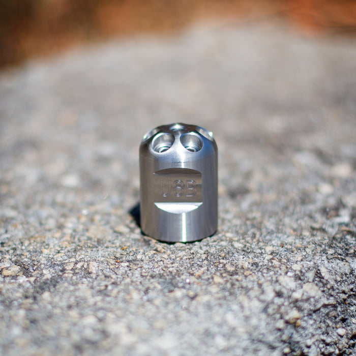 Stainless steel Digger Nozzle for sewer jetting, forward‑jet design with no rear jets to push debris and scale out of small pipes; manually pushed nozzle ideal for short runs under 100 feet during pipe‑lining prep, shown on a rough concrete surface for detailed product display.
