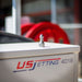 USJ Penetrator 1/2-inch sewer jetting nozzle resting on a US Jetting 4018 machine, close-up of brass forward jet and six rear jet ports designed for penetrating hard blockages like packed debris or ice; high‑pressure drain cleaning nozzle for 4018 jetters with adapters available for other hose sizes.