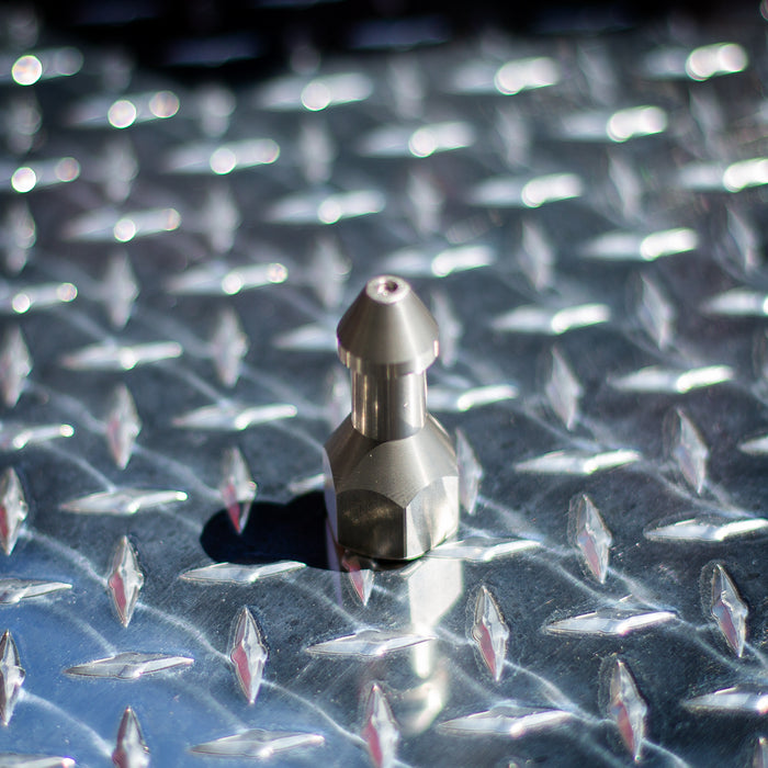 USJ Penetrator 1/2-inch stainless steel sewer jetting nozzle on reflective diamond plate surface, close-up of precision-machined forward jet and six rear jet ports engineered to break through hard blockages like packed debris or ice; high‑pressure 4018 jetter nozzle with adapters available for other hose sizes.