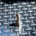 USJ Penetrator 1/2-inch stainless steel sewer jetting nozzle on reflective diamond plate surface, close-up of precision-machined forward jet and six rear jet ports engineered to break through hard blockages like packed debris or ice; high‑pressure 4018 jetter nozzle with adapters available for other hose sizes.