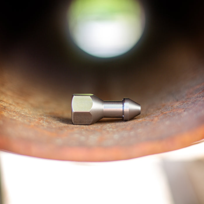 USJ Penetrator 1/2-inch stainless steel sewer jetting nozzle inside a rusted pipe, close-up of precision-machined forward jet and six rear jet ports engineered to cut through hard blockages like packed debris or ice; high‑pressure 4018 jetter nozzle with adapters available for other hose sizes.