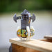 Close‑up of an ENZ Turbo Chain Scraper nozzle resting on a wooden surface, showing its heavy‑duty rotating chain head, serrated cutting edges, adjustable chain lengths, and white centralizing skids. Industrial sewer jetting tool engineered for removing concrete, roots, and grease from 3–8 inch pipes, built for rugged conditions and compatible with jetting machines requiring at least 8 GPM.